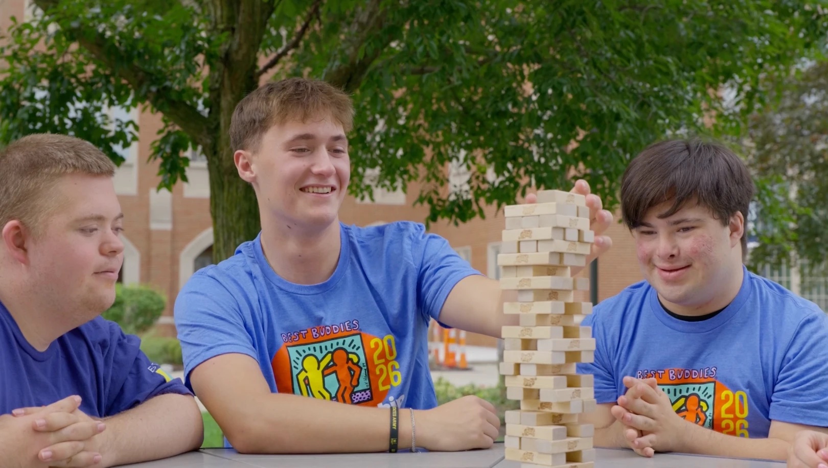 Three Best Buddies participants playing Jenga outdoors